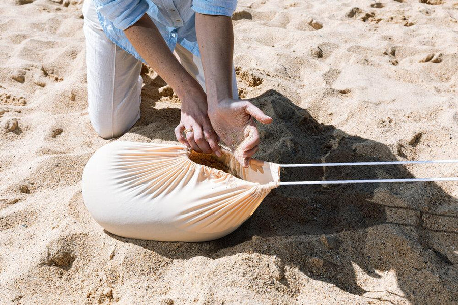 filling the sand bag of a beach tent