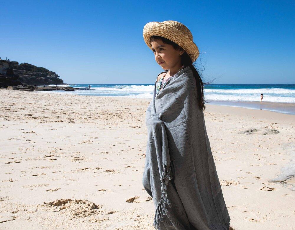 Child on beach wrapped in Ozoola Turkish beach towel