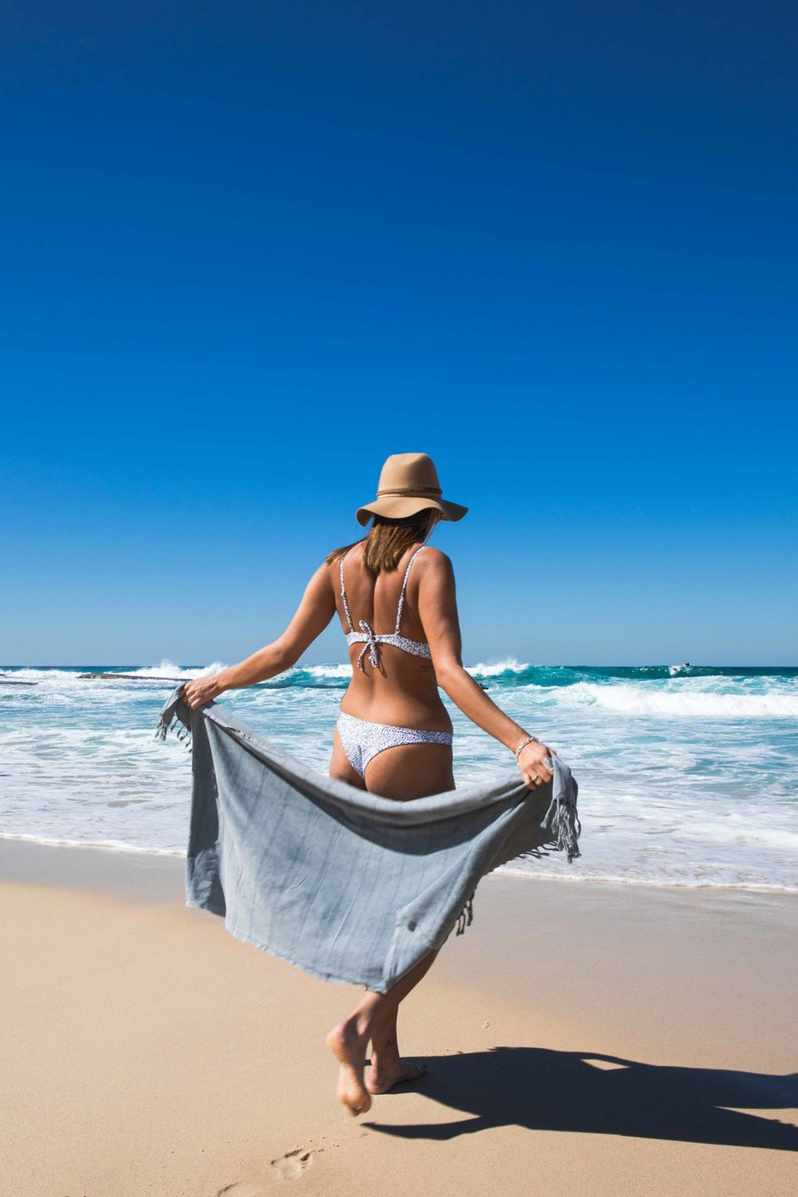 Woman on beach with Ozoola Turkish beach towel in grey stonewash